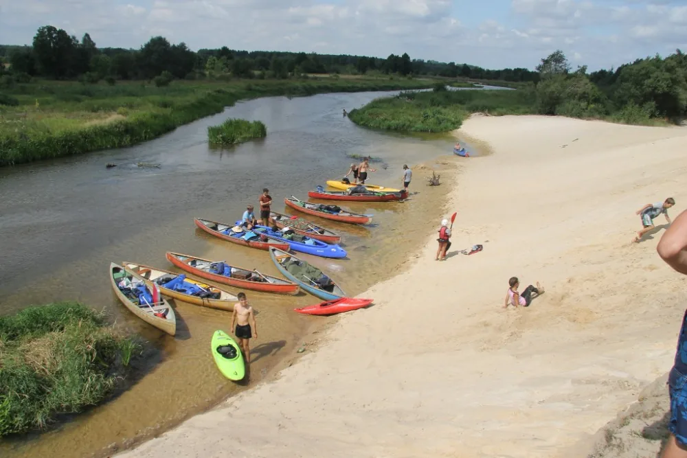 Vodácký tábor — lodě na pláži u řeky